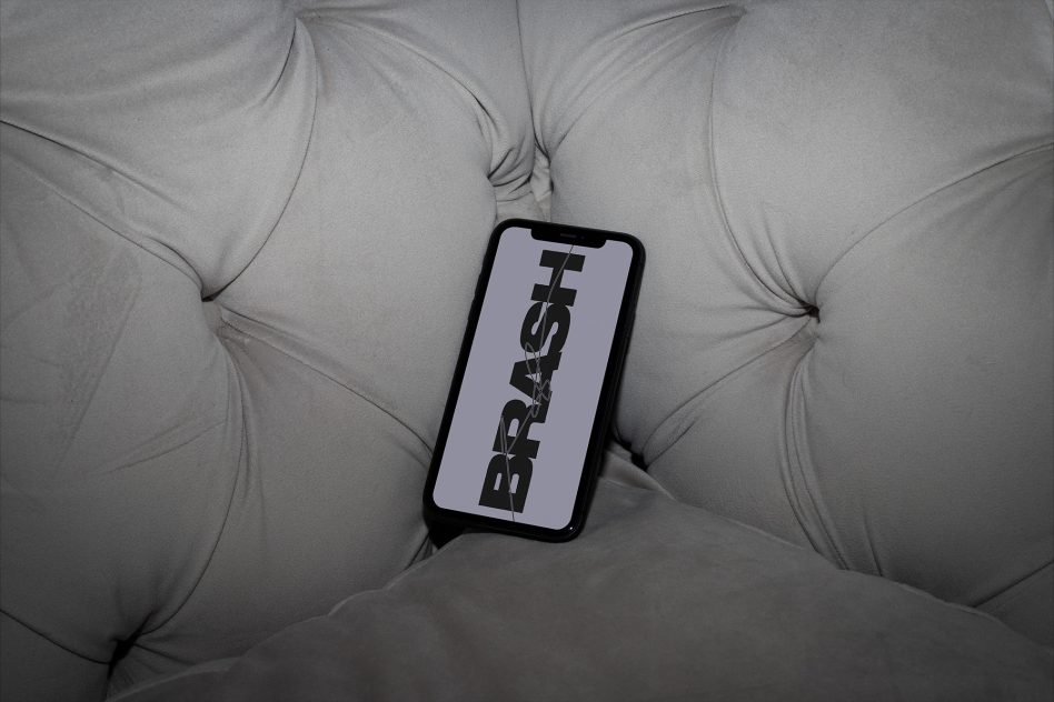 Smartphone with bold graphic font mockup on cushioned couch, sleek design for modern font presentation, ideal for graphic designers.